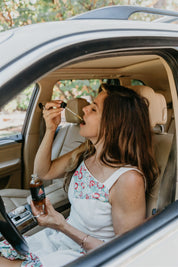Woman sitting in a car, drinking from tincture bottle of Mythic Medicine