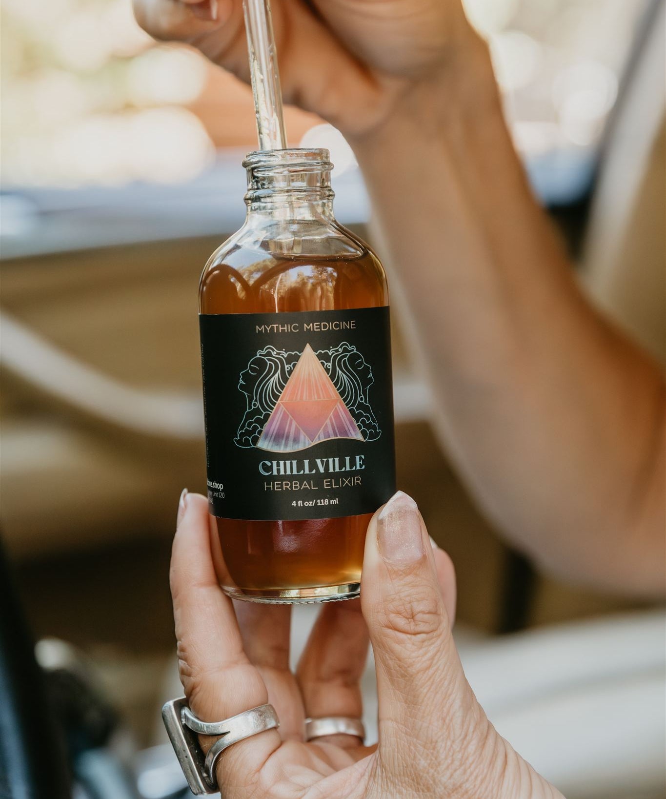 Bottle of Chillville Herbal Balm with a dropper held by a hand.