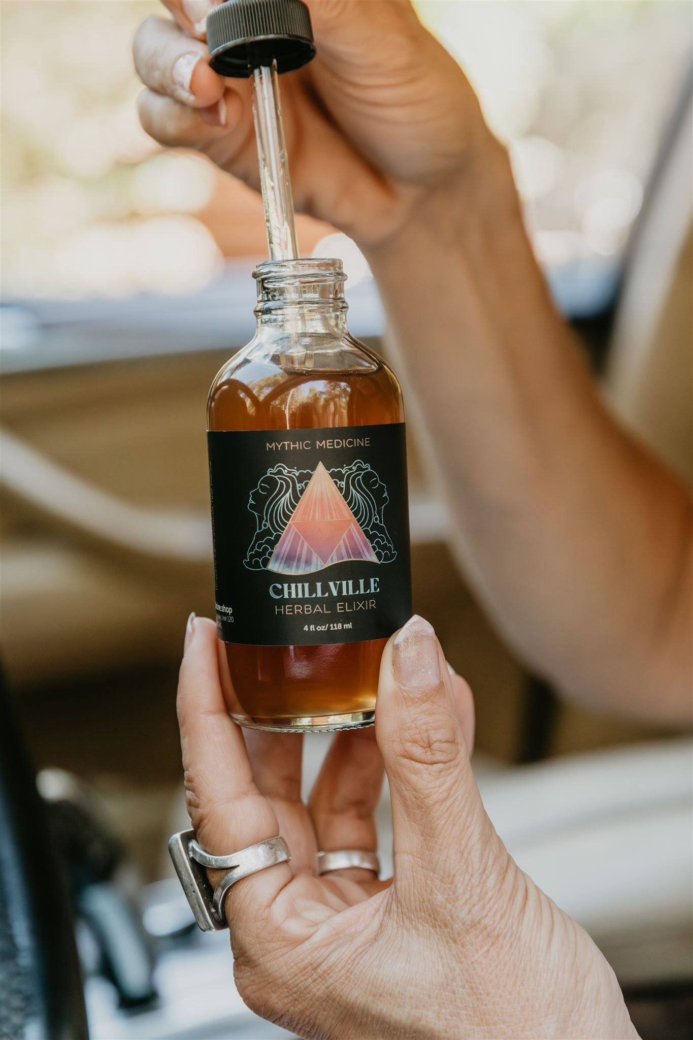 Bottle of Chillville Herbal Balm with a dropper held by a hand.