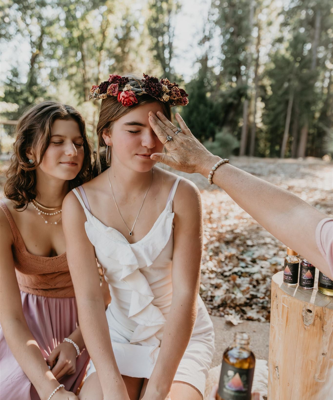 Two women outdoors with one applying Mythic Medicine to the other's face, surrounded by nature.