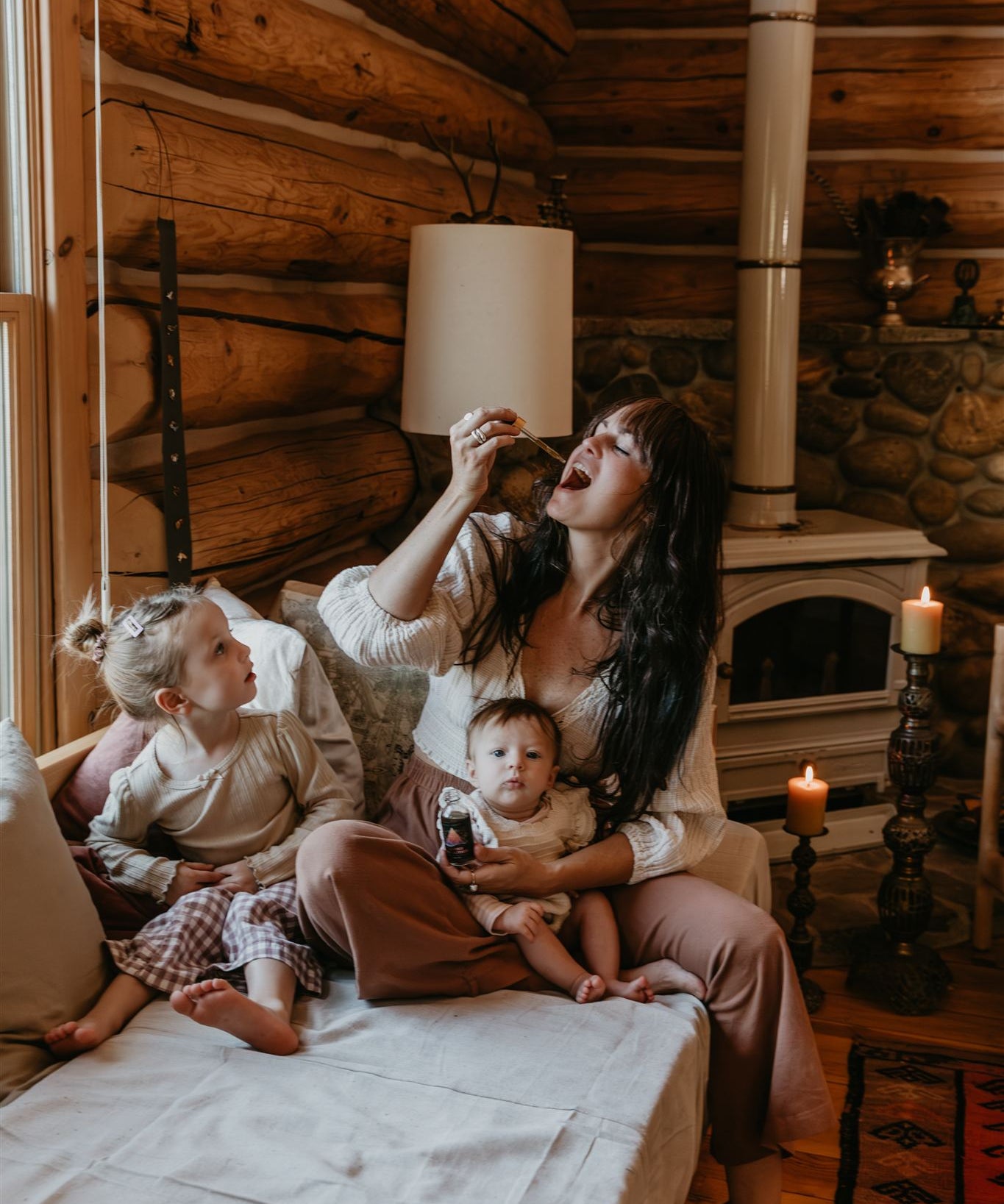 Woman and two children sitting on a bed in a cozy log cabin.