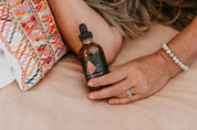 Person holding a bottle of 'Sleep & Dream' tincture on a textured surface.