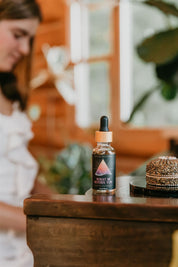 Bottle of 'What If' tincture on a wooden surface with a blurred background