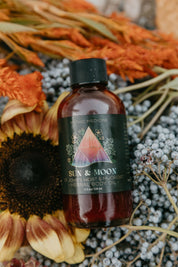 Bottle of Sun & Moon herbal Mythic Medicine body oil surrounded by dried flowers and plants