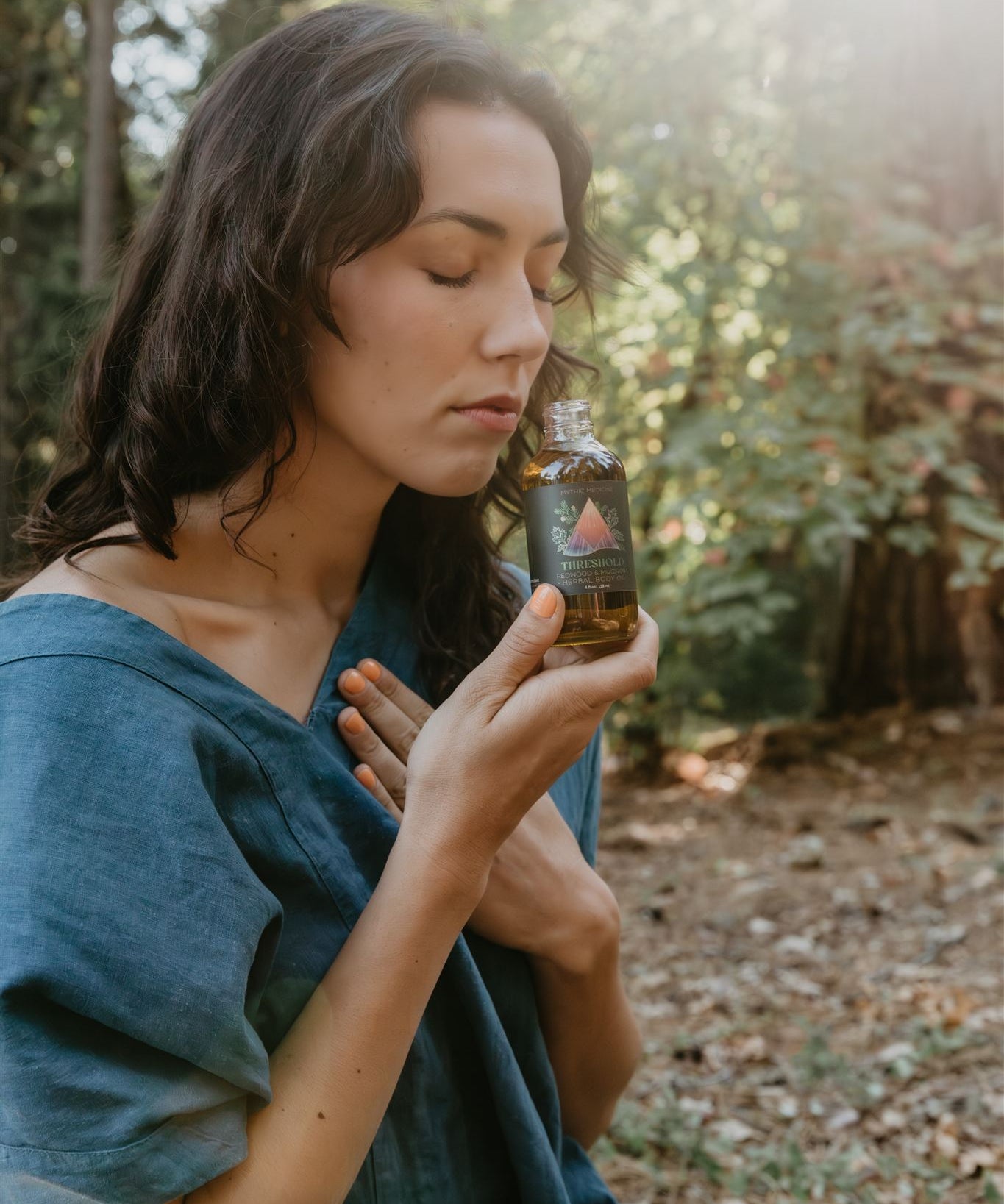 Woman holding a bottle of Mythic Medicine in a forest setting