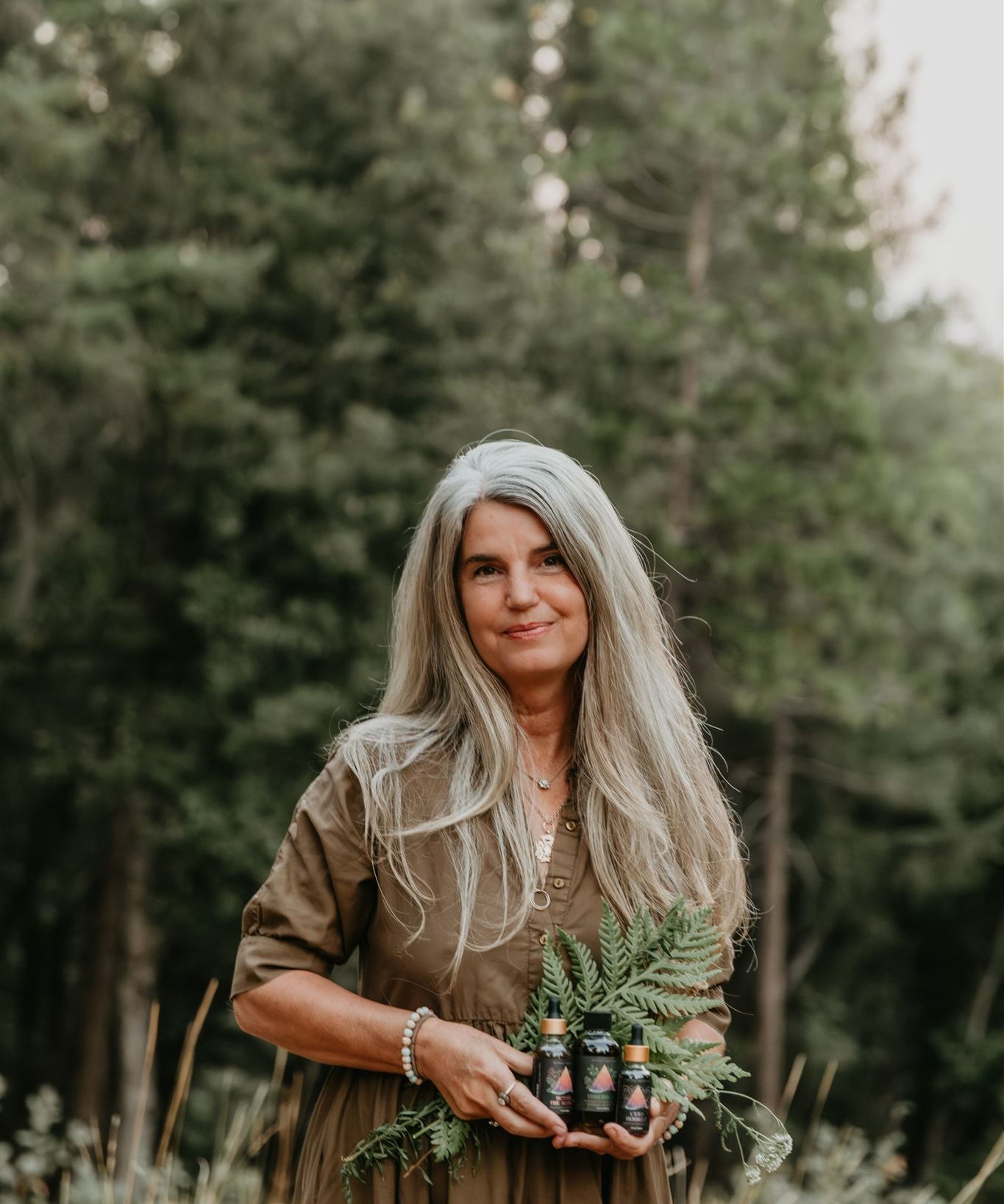 Woman holding plants and mythic medicine in a forest setting