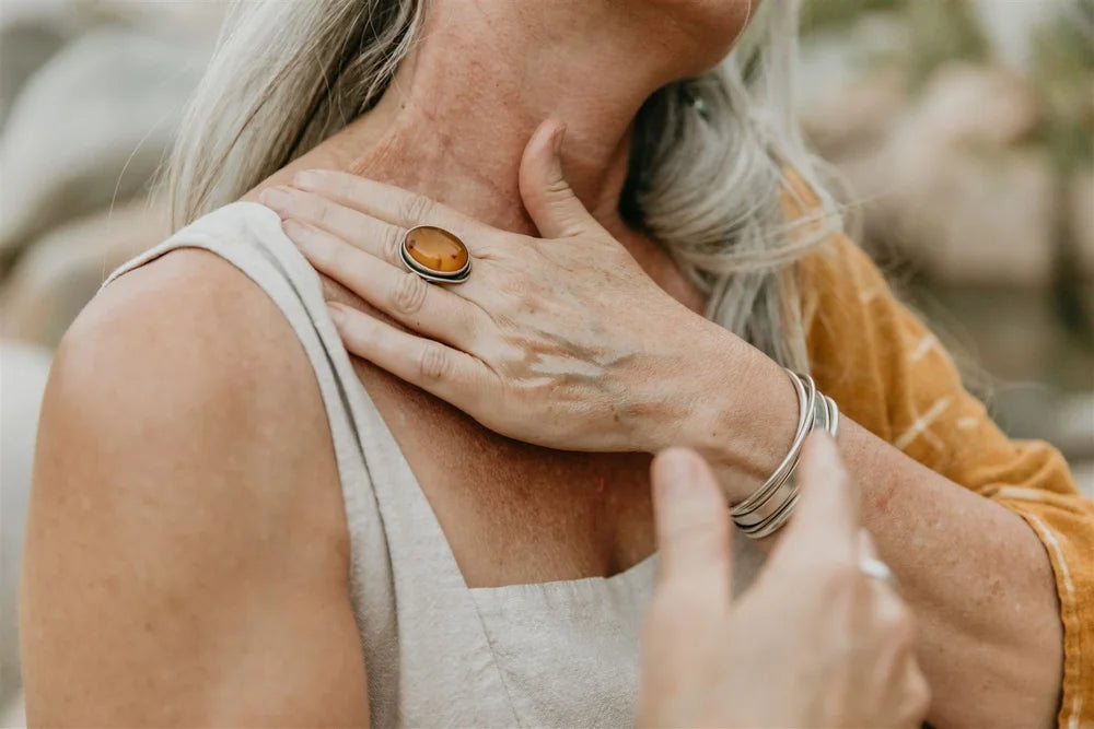 Person wearing a ring on their finger with a blurred natural background