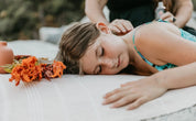 Woman receiving a massage outdoors with flowers nearby