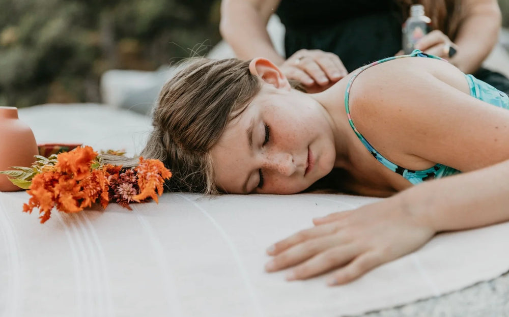 Woman receiving a massage outdoors with flowers nearby