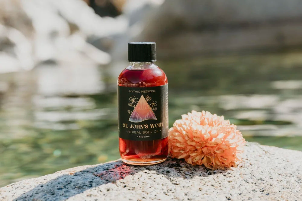 Bottle of St. John's Wort tincture on a rock with water and flowers in the background